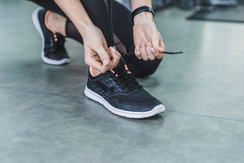 cropped shot of woman lacing up sneakers before training